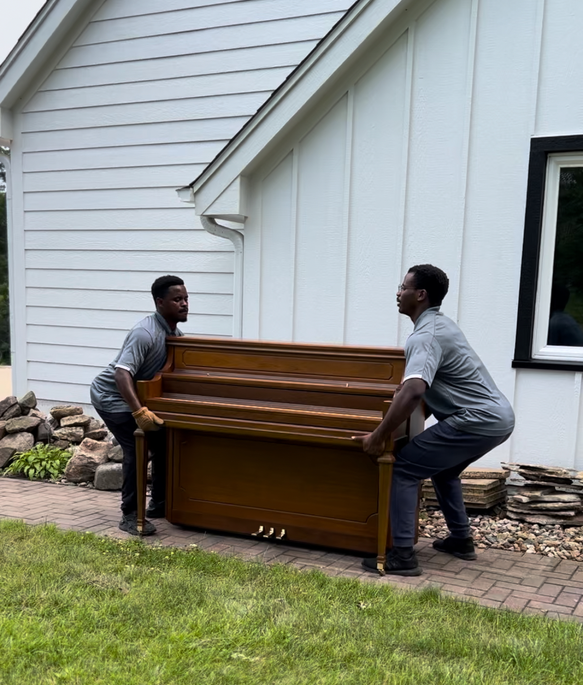 Speciality 1 Midwest Moving Pros crew safely moving a piano with specialty equipment at a Des Moines home.
